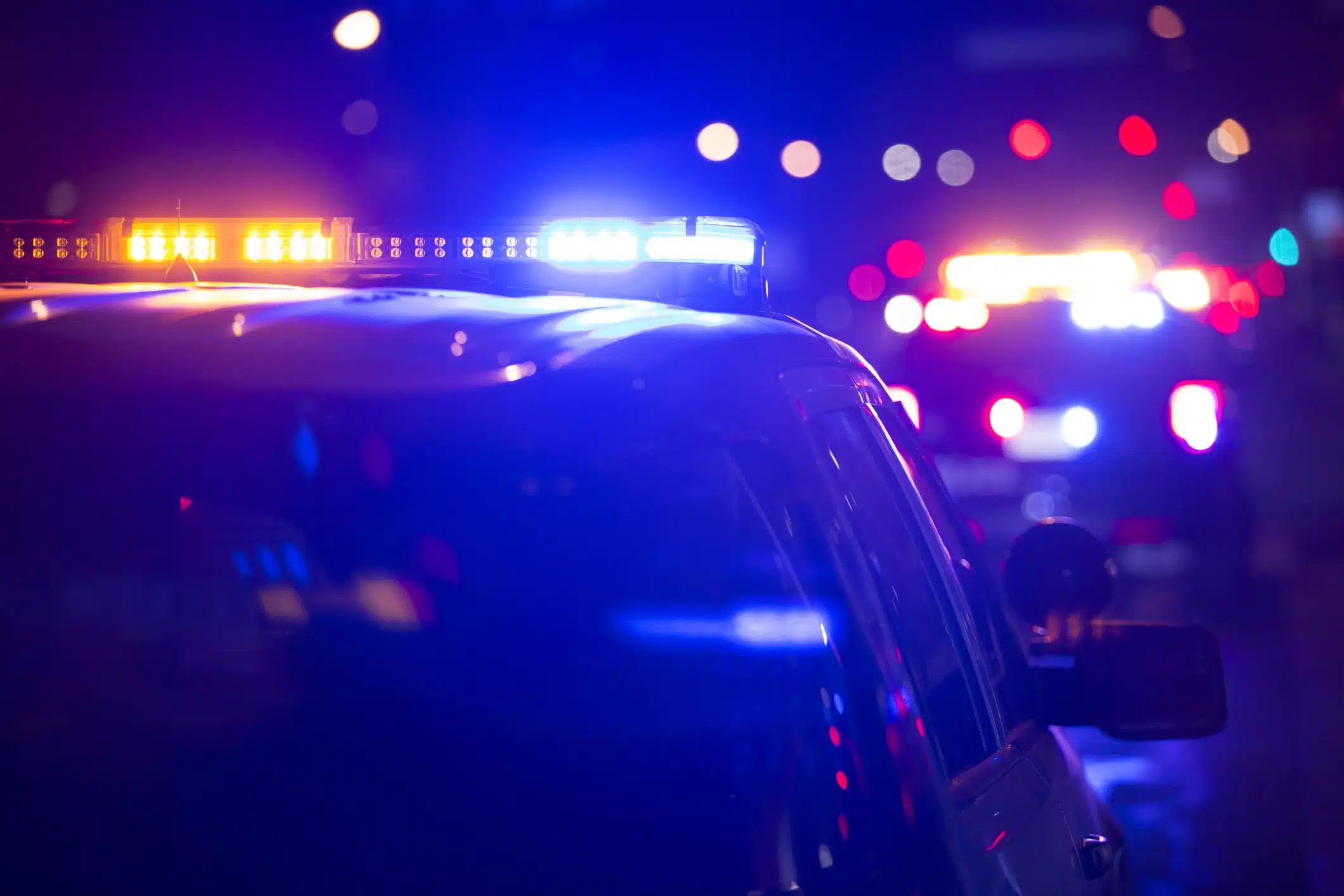 Two police cruisers with lights flashing at night